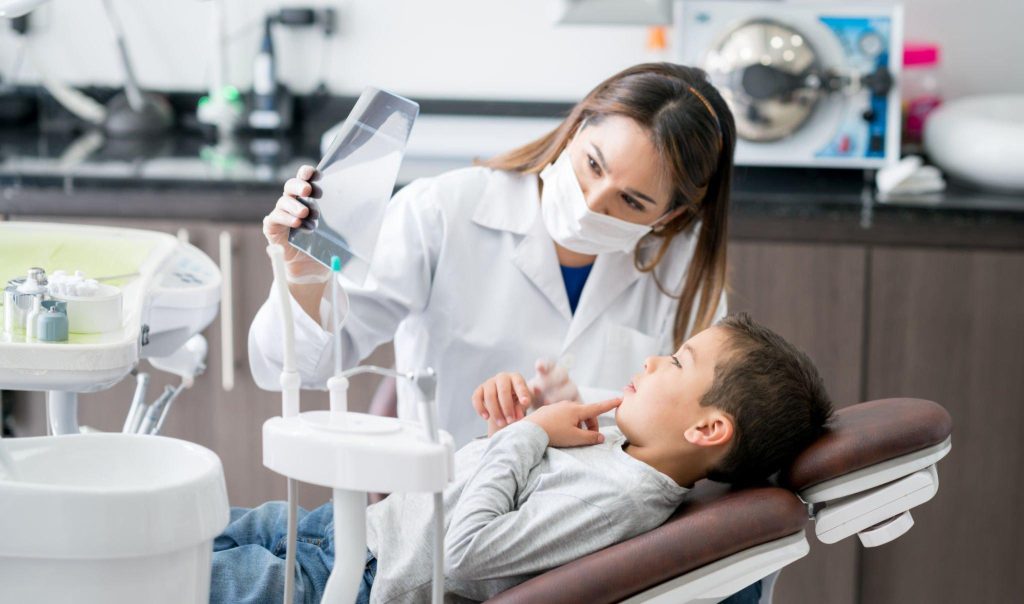 Dentist showing dental x-ray to a child in a consultation