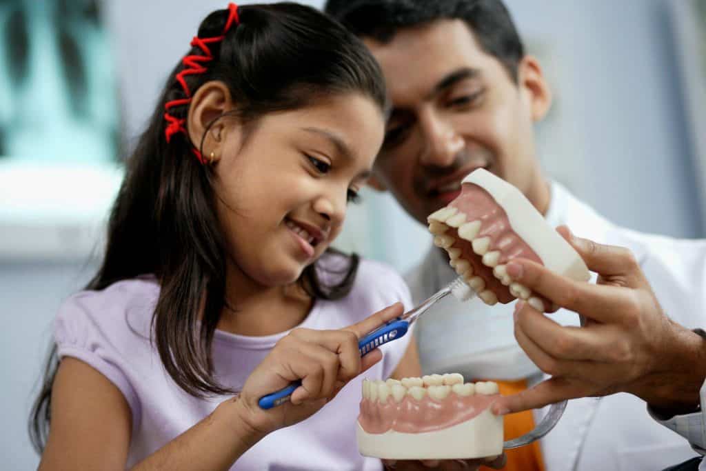 Young girl learning to brush teeth with a dentist using a dental model at Los Algodones Dentists Guide